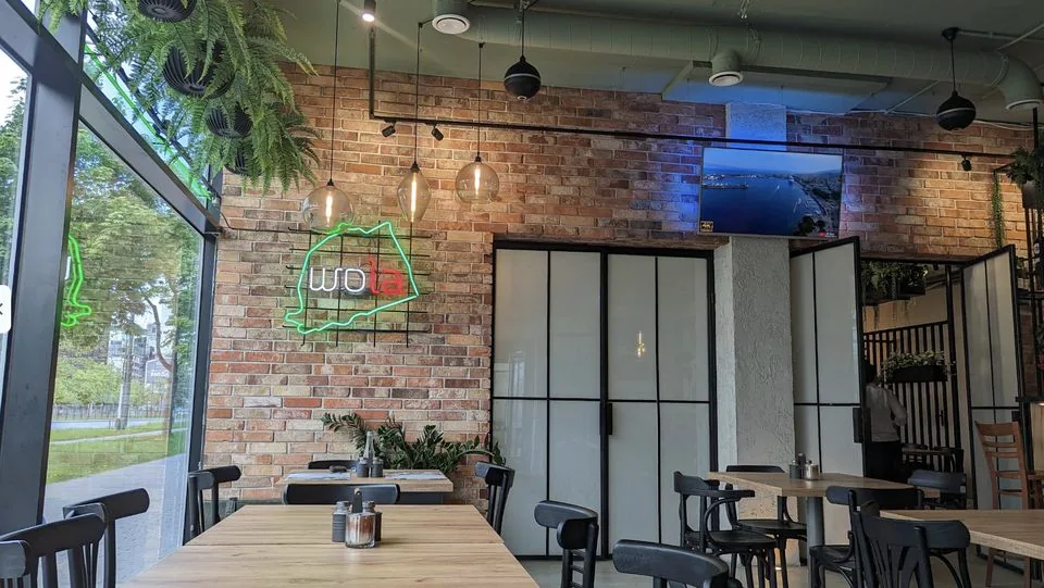 Wnętrze restauracji Brindisi: cegła, dębowe stoły, neon Wola